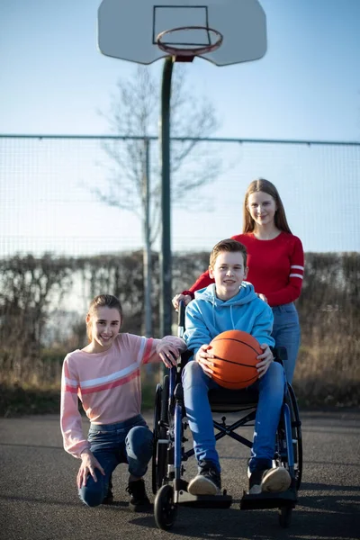 Tekerlekli sandalyedeki çocuğun portresi. Frizbiyle basketbol oynuyor. — Stok fotoğraf