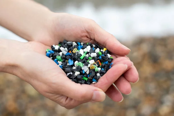 손으로 플라스틱 알갱이들을 해변을 가까이서 — 스톡 사진