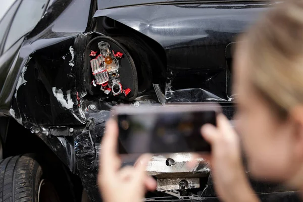 女性司机在手机上拍摄车祸后损坏车辆的照片以申请保险 — 图库照片