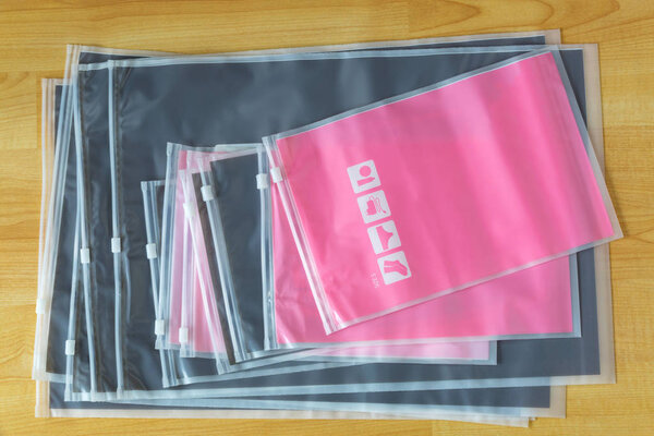 Пластиковая застежка-молния, герметичные сумки для хранения носков, нижнего белья, электронных гаджетов, косметики и т.д. вид сверху на деревянном фоне
