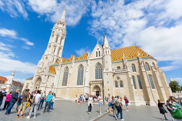 Mensen lopen in de voorkant van Matthias kerk, de kerk van de dame van onze Buda, in Boedapest, Hongarije — Stockfoto