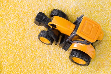 Polenta üzerinde sürüş Mini sarı traktör, sarı Mısır unu, İrmik taneleri.