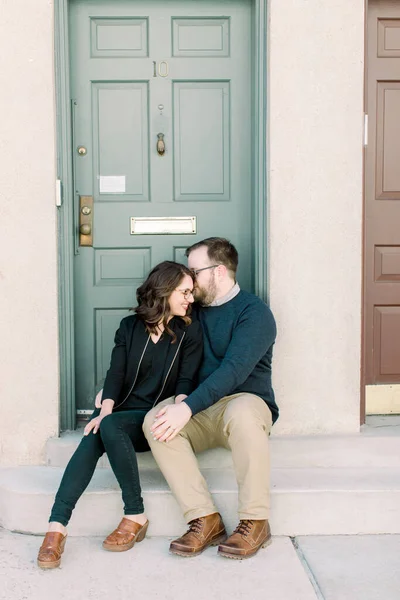 A young married couple sitting on the porch of their new house