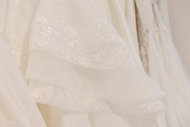 Güzel, beyaz bir gelinlik zarif, gösterişli, karmaşık nakış ve ince kumaş detaylarıyla asılı duruyor..