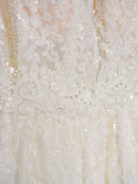 Parlak boncuklu narin dantel güzel aydınlatılmış bir çevrede çarpıcı bir gelinliğin altını çiziyor..