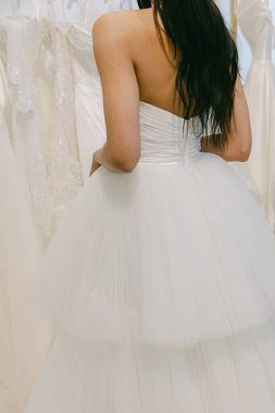 Bir gelinlik mağazasında gelinlik provası sırasında gelinliğin arasında duruyor..