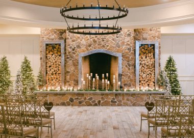 Taş şömineli ve yanıp sönen ışıklı bir kış düğünü için davet edilen kapalı bir alan..