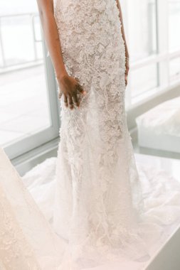 Enfes dantelli ve modern siluetli göz kamaştırıcı bir gelinlik, parlak bir sergi salonunda sergileniyor..