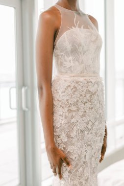 Model, zarif dantelli güzel bir gelinlik sergiliyor, sakin bir atmosferde gelinlik modasını vurguluyor..