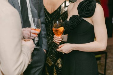 Katılımcılar zarif giyinme ve dekorasyonun yer aldığı şık bir akşam etkinliğinde renkli kokteyller içerken sosyalleşiyorlar.