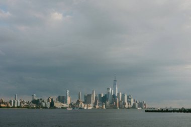 New York şehrinin gökyüzü öğleden sonra aydınlığında yükselen binalar ve gri bir gökyüzü yer alıyor..
