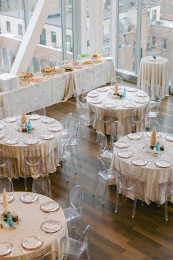 Bu mekânda şık dekorları ve lezzetli yemek seçenekleriyle lüks bir toplantı için hazırlanmış çok sayıda yuvarlak masa bulunuyor..