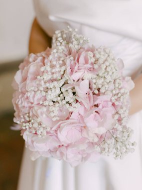 Bir gelin, zarif çiçeklerle dolu göz kamaştırıcı pembe ve beyaz bir buket tutar ve düğün gününe neşe katar..