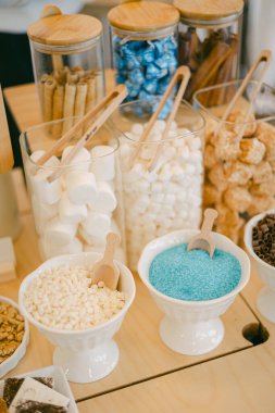 Parlak renkli tatlı malzemeler cam kaplarda düzenlenir. Bayramlık bir etkinlikte tatlı süslemesi için hazırdır..