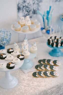 Süslü bir tatlı masasında kış temalı kapkekler, kurabiyeler ve neşeli bir toplantı için ikramlar sergileniyor..