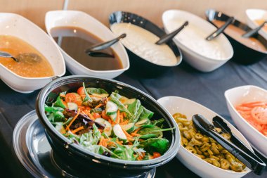 Renkli bir salata, bol soslu seçenekler sunulur. Rahatlatılmış bir yemek salonunda, canlı malzemeler sergilenir..