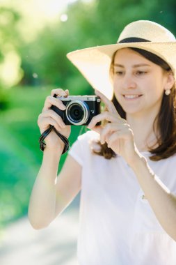 Elinde kamera olan bir kız, kafasında şapka var.