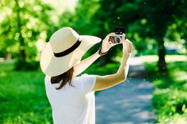 Elinde kamera olan bir kız, kafasında şapka var.