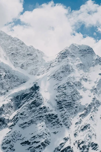 Close-up van torenhoge scherpe besneeuwde bergtoppen met wolken — Stockfoto