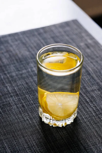 Rodajas de limón dentro de un vaso con agua en una mesa de madera — Foto de Stock