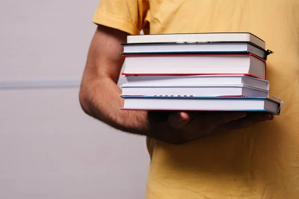 Bir adamın elinde bir yığın kitap.