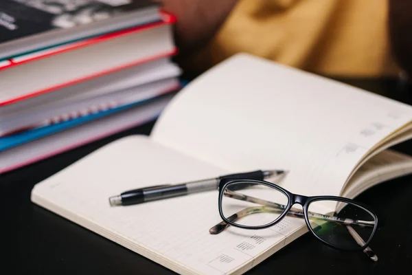 Matita con occhiali su un libro sullo sfondo di un uomo — Foto Stock