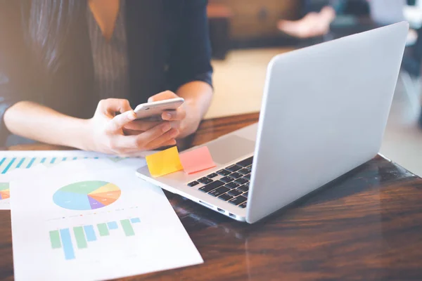 Businessman uses a phone to work on charts and graphs that show results.