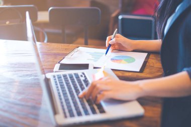 İş kadını dizüstü bilgisayarlar ve analiz çalışma çizelgeleri ve sonuçları gösteren grafikler. Eli kalem tutan ve grafiğe işaret eder. İş Analizi ve strateji.