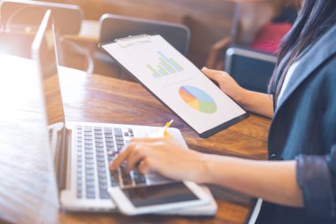 İş kadını dizüstü bilgisayarlar ve analiz çalışma çizelgeleri ve gösteren sonuçlar grafikler.