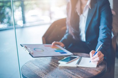 Not etmek üstünde yazma ve Analizi grafikleri ve ofiste işlenen grafikler kullanarak iş kadın el.