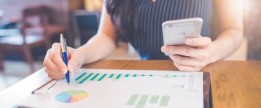 Çizelgeler ve grafikler bir kalemle sonuçları göster tarih yazma ve bir smartphone kullanarak kadın eli. Web afiş.