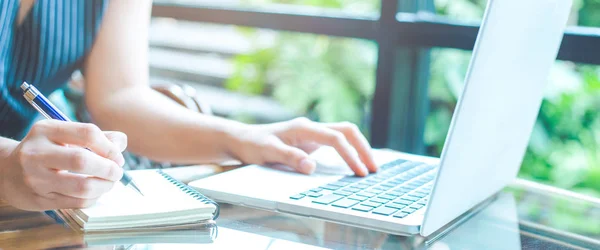 İş kadın el not etmek üstünde kalemle yazma ve bir dizüstü bilgisayar kullanarak. Web afiş.