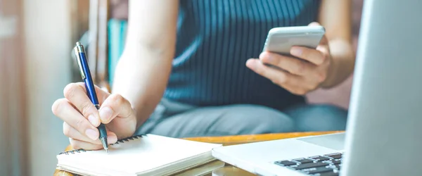 İş kadın el bir not etmek üstünde kalemle yazma ve bir cep telefonu kullanarak. Web afiş.