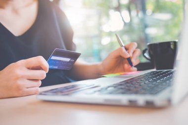 İş kadın eli bir kredi kartı tutan ve online alışveriş için bir dizüstü bilgisayar kullanır.