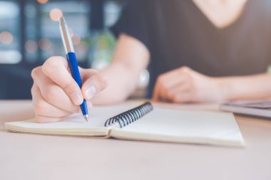 Kadın el üstünde bir defter bir kalemle yazma.