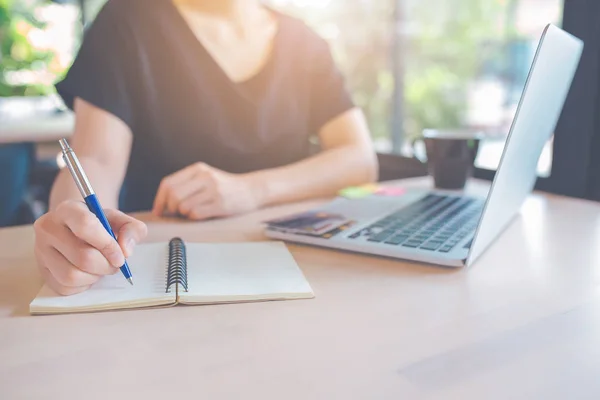 Vrouw hand is het schrijven op een notitieblok met een pen. Op de tafel, ther — Stockfoto