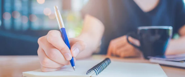 Mujer de negocios mano está escribiendo en un bloc de notas con un bolígrafo . — Foto de Stock