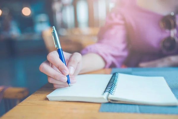 Die Hand der Frau schreibt mit einem Stift auf ein Notizbuch. — Stockfoto