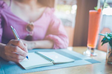 Kadın el üstünde bir defter bir kalemle yazma.