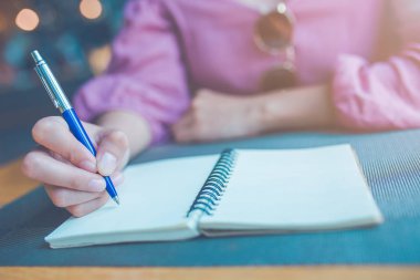 Kadın el üstünde bir defter bir kalemle yazma.