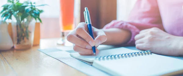 La mano de la mujer está escribiendo en un bloc de notas con un bolígrafo. . — Foto de Stock