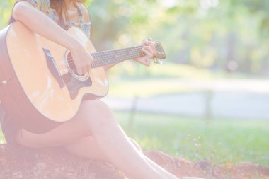 Kadın bahçede akustik gitar çalıyor..