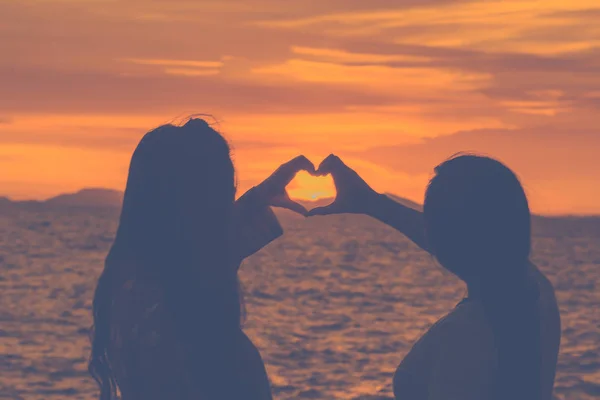 Silhouette woman hand is making a heart-shaped symbol at sunset — Stock Photo, Image