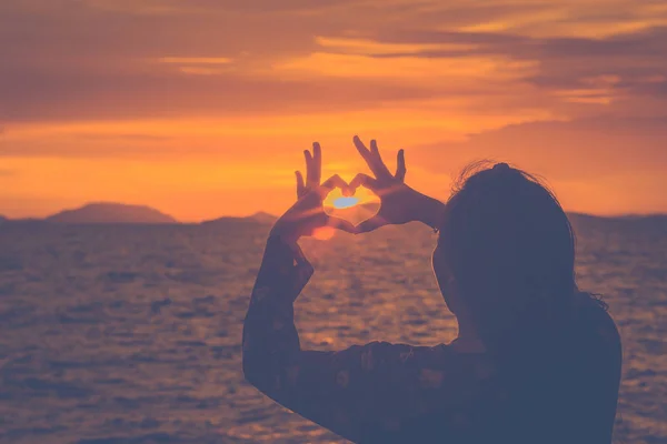 Silhouette woman hand is making a heart-shaped symbol at sunset — Stock Photo, Image