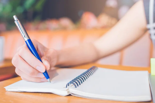 Femme écriture à la main sur un bloc-notes avec un stylo dans le bureau . — Photo