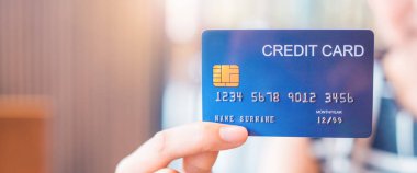 Kadın el mavi bir kredi kartı tutar.