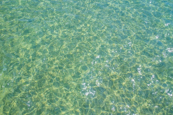 Berrak su yeşili ve güneşten yansımaları ile küçük dalgalar, — Stok fotoğraf