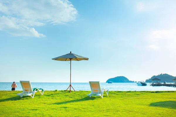 해변 의자와 해변 우산은 해변의 잔디밭에 있습니다. Se — 스톡 사진