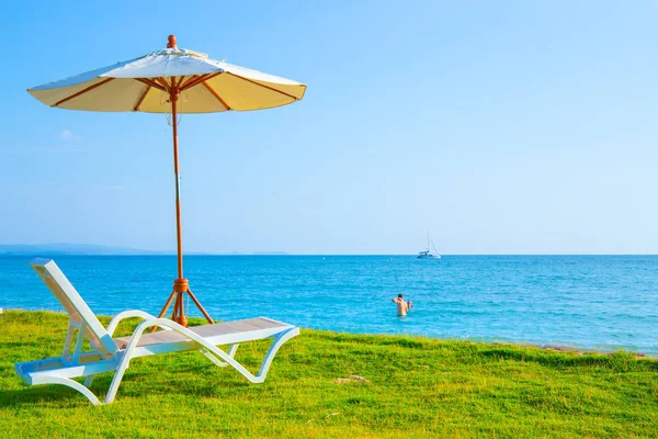 Plajdaki çimenlikte plaj koltukları ve plaj şemsiyeleri bulunmaktadır. Se — Stok fotoğraf