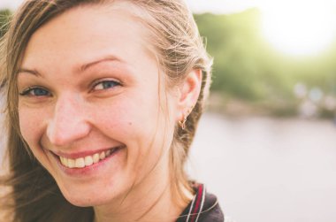 Sarışın genç kadın geniş günbatımı arka planı gülümsüyor